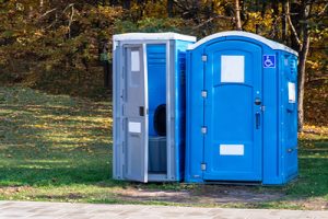 ada porta potty next to a normal porta potty in a field