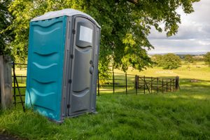 porta potty in a field near a gate